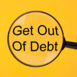 Hand holding magnifying glass over text Get Out Of Debt.